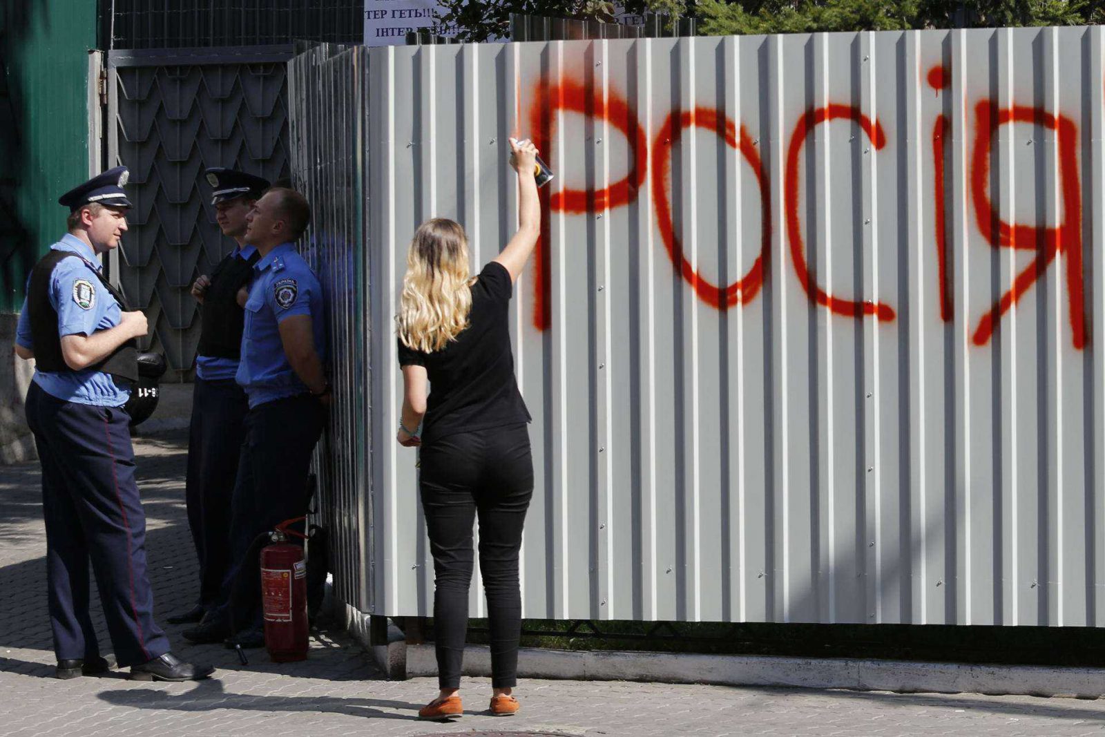 Police stand guard as an activist sprays the word 'Russia' on the barrier around Ukrainian television channel "Inter," which protesters say has an anti-Ukrainian stance, in Kyiv, Ukraine September 5, 2016. photo by Maxym Marusenko *** Please Use Credit from Credit Field ***